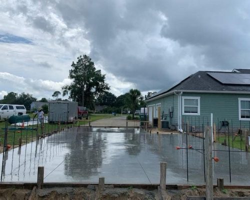 Concrete poured in backyard of house. Construction work in progress.