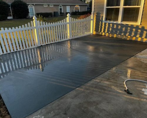 A concrete patio with a white picket fence, creating a charming outdoor space for relaxation and gatherings.